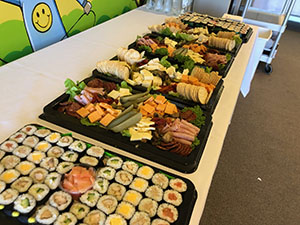 Platters of mini-sushi, ham, salami, cheese and crackers.